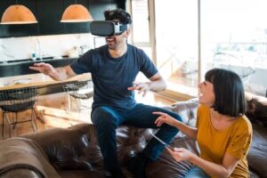 Man wearing virtual reality goggles and a girl on a couch